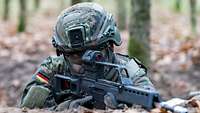 Ein Soldat mit Gewehr im Anschlag iegt im Gelände.