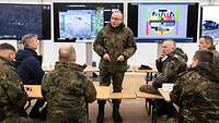 Generalinspekteur Carsten Breuer steht vor sitzenden Soldaten. Hinter ihm stehen große Bildschirme.