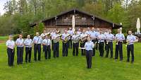 Musiker mit Instrumenten auf einer Wiese vor einer Almhütte