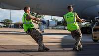 Zwei Soldaten ziehen am Betankungsschlauch eines Transportflugzeuges vom Typ Airbus A330 MRTT.