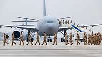 Soldaten steigen aus einem Transportflugzeug vom Typ A330 MRTT und gehen hintereinander auf dem Flugfeld.