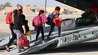 People board a military aircraft during an evacuation