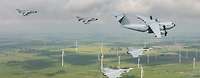 Fünf militärische Flugzeuge fliegen über einer Landschaft mit Windrädern.