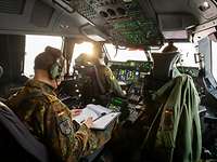 Generalleutnant Freuding sitzt hinter zwei Soldaten im Cockpit eines A440M und liest ein Dokument.