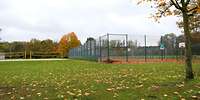 Blick auf verschieden große Sportflächen, teils mit Zäunen, umgeben von Bäumen