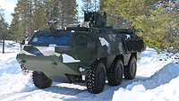Ein militärisches Fahrzeug mit sehr großen Reifen steht im Wald. Der Boden ist mit Schnee bedeckt.