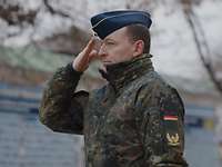 Ein Soldat grüßt mit der flachen Hand an der Kopfbedeckung.