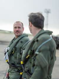 Zwei Soldaten gehen nebeneinander. Im Hintergrund steht ein Kampfflugzeug.