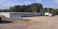 Blick auf ein flaches Containergebäude mit großer Fläche davor.