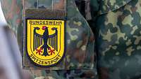 Ein gelbes Abzeichen mit Bundesadler und dem Schriftzug „Bundeswehr Spitzensport“ auf einer Uniform.