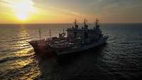 Drei Versorgungsschiffe der Marine auf See bei Sonnenuntergang