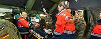 Menschen in Uniformen der Bundeswehr und der Malteser stehen in einem Zelt um einen Patienten auf einer Trage.
