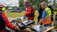 Ein Arzt sowie Kräfte von Bundespolizei und Feuerwehr transportieren eine verletzte Person auf einer Trage.