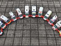 Luftbildaufnahme: 10 Rettungswägen von oben stehen mit ihrer Besatzung auf einem Platz