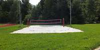 Ein Volleyballspielfeld umringt von Rasen neben einer Tartanbahn.