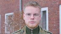 Porträt von einem Soldaten vor einem roten Backsteingebäude.