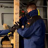 Mehrere Soldatinnen und Soldaten stehen unter Deck und halten einen Balken.