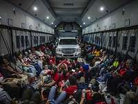 Evacuees sit together in a transport aircraft.