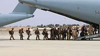 Military personnel boarding a transport aircraft