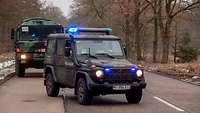 Ein Bundeswehrfahrzeug der Feldjäger fährt mit Blaulicht vor einem türkischen Militär-Lkw.