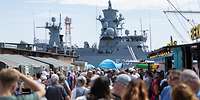 Viele Besucher gehen im Hafen vor einem Schiff.