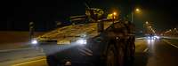 A Bundeswehr tank drives on a motorway at night.