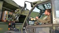 Ein Soldat sitzt in einem Fahrzeug mit Teleskoplader und lädt Material in einen LKW.