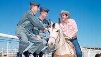 Zwei Luftwaffensoldaten sitzen auf einem Zaun und unterhalten sich mit einem Cowboy.