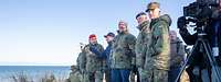 Boris Pistorius und mehrere Soldaten stehen am Strand in den Dünen und beobachten etwas.