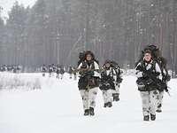 Links und rechts versetzt, mit Rucksack und Waffe, marschieren Soldaten gruppenweise auf. einem Weg.