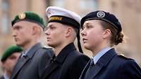 Zwei Soldaten und eine Soldatin verschiedener Teilstreitkräfte stehen in Formation.