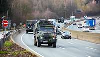 Militärfahrzeuge fahren auf der Autobahn zwischen zivilen Fahrzeugen