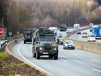 Militärfahrzeuge fahren auf der Autobahn zwischen zivilen Fahrzeugen