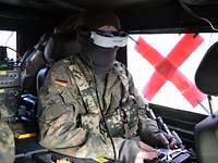 In einem Kraftfahrzeug bedient ein sitzender Soldat mit einer Bildschirmbrille eine Drohne.