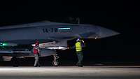 Ein deutscher und spanischer Wart weisen einen Eurofighter ein, nachdem dieser nachts gelandet ist.