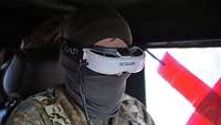 Ein Soldat mit einer weißen FPV-Brille mit der Aufschrift Fat Shark sitzt in einem Fahrzeug.