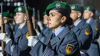 Soldaten vom Wachbataillon sind mit Gewehren angetreten. Im Vordergrund ist eine Soldatin zu sehen.