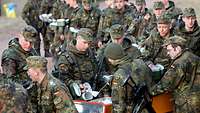 Soldaten stehen Schlange an der Essensausgabe im Gelände