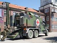 Sanitäter verladen einen Verletzten in den Transportraum eines militärischen Fahrzeugs.