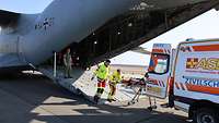 Ziviler Rettungsdienst beim ausladen eines Patienten aus dem Flugzeug, direkt in einen Rettungswagen