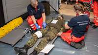 Zwei Sanitäter knieen neben einem Patienten in Bundeswehruniform