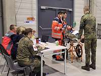 Ein Soldat auf einer Liege wird von sechs anderen Menschen betreut