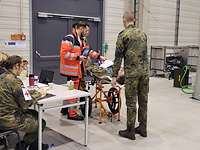 Ein Soldat auf einer Liege wird von sechs anderen Menschen betreut