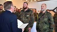 Minister Pistorius überreicht an zwei Soldaten Urkunden.