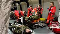 Soldaten liegen auf Tragen und werden von Rettungssanitätern versorgt.