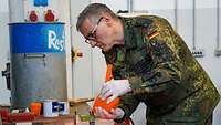 Ein Soldat gießt in einer Werkstatt eine Masse in eine Form.