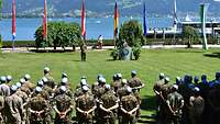 Auf einer Wiese am Ufer des Bodensees sind Soldaten in Formationen angetreten, vor ihnen Flaggen.