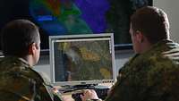 Zwei Soldaten sitzen vor einem Monitor, auf dem eine Digitale Karte dargestellt wird.