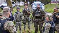 Soldatinnen und Soldaten der Militärpolizeien verschiedener Nationen stehen in einem Kreis und tauschen sich aus.