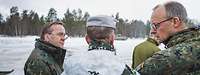 Merz and Pistorius talking with soldiers in the exercise area in winter conditions.